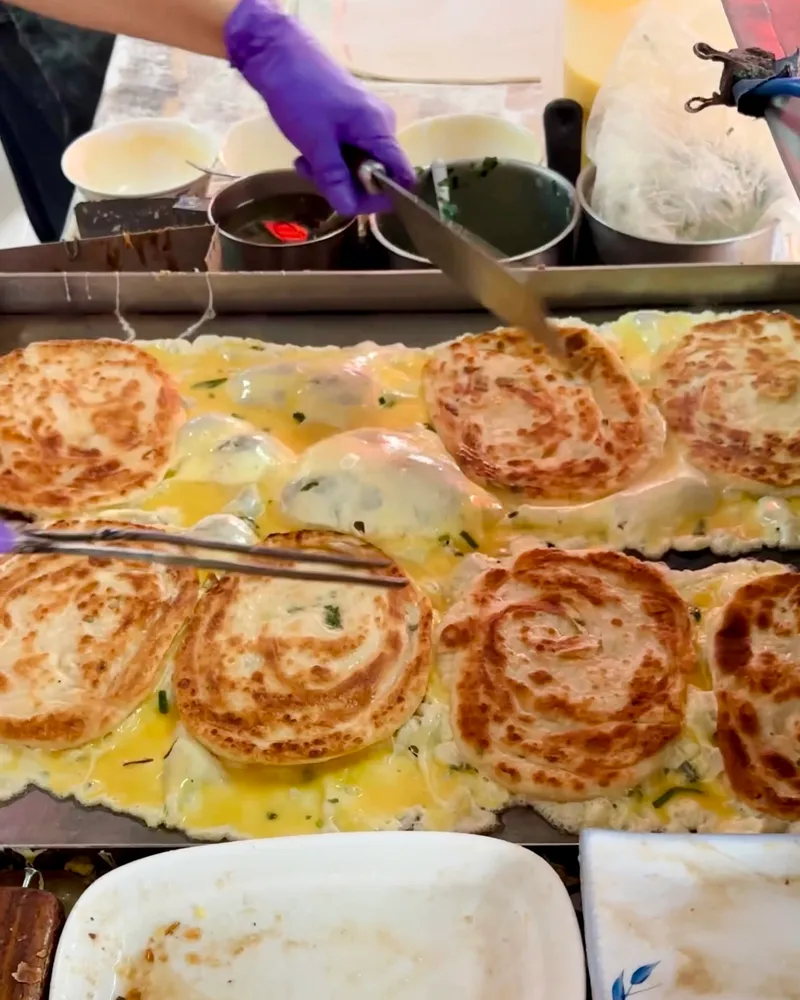 Scallion pancake being prepared with egg